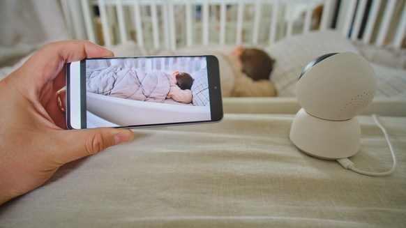 Watching a child sleeping in a room from a phone through a camera xkwx monitor child device phone camera security wireless baby safety display remote video smart crib newborn care infant radio watch s ...