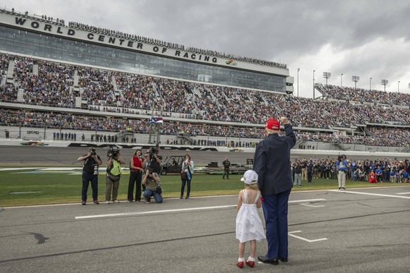 February 16, 2025, Daytona, Fl, United States: U.S President Donald Trump, accompanied by his granddaughter Carolina Trump, wave to the crowd before the start of the NASCAR Daytona 500 race at Daytona ...