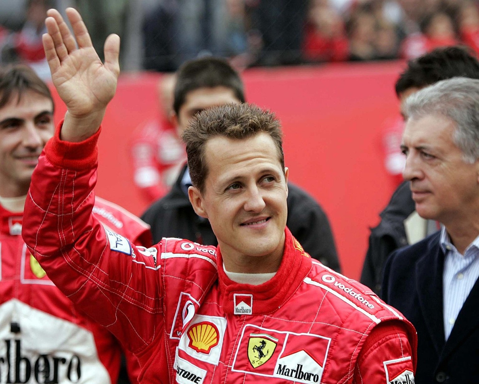 F1 World Champion Michael Schumacher waves to fans at the Monza racetrack, Italy, during a demonstration of the Scuderia Ferrari, Sunday, Oct. 31, 2004. (AP Photo/Luca Bruno)