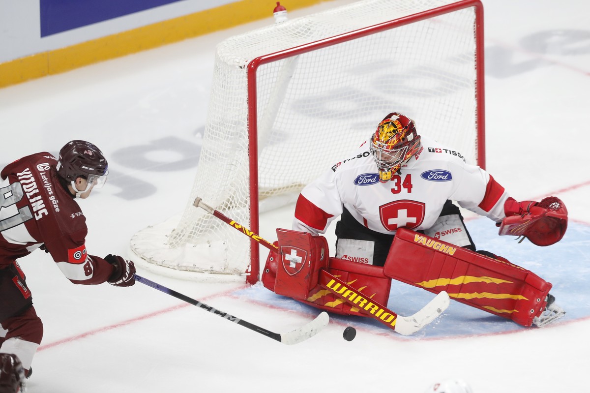 epa12052430 Latvia's Raimonds Vitolins (L) in action against Switzerland's goalkeeper Stephane Charlin during the friendly international ice hockey match between Latvia and Switzerland in Ri ...