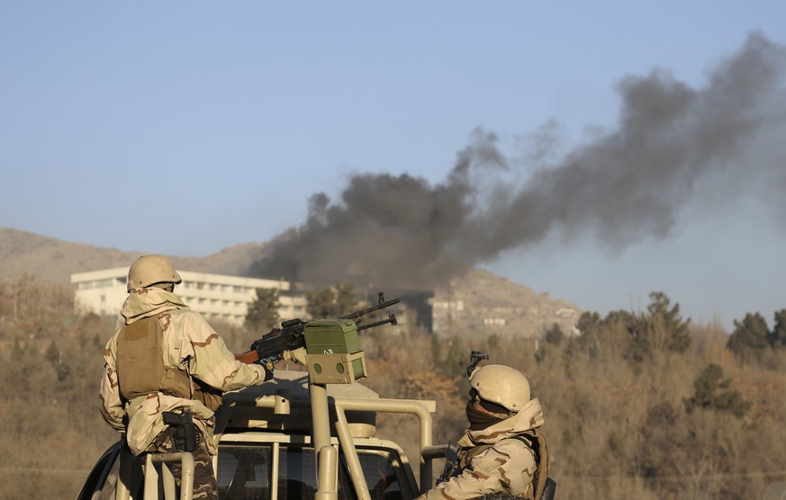 Afghan security personnel stand guard as smoke rises from the Intercontinental Hotel after an attack in Kabul, Afghanistan, Sunday, Jan. 21, 2018. Gunmen stormed the hotel in the Afghan capital on Sat ...