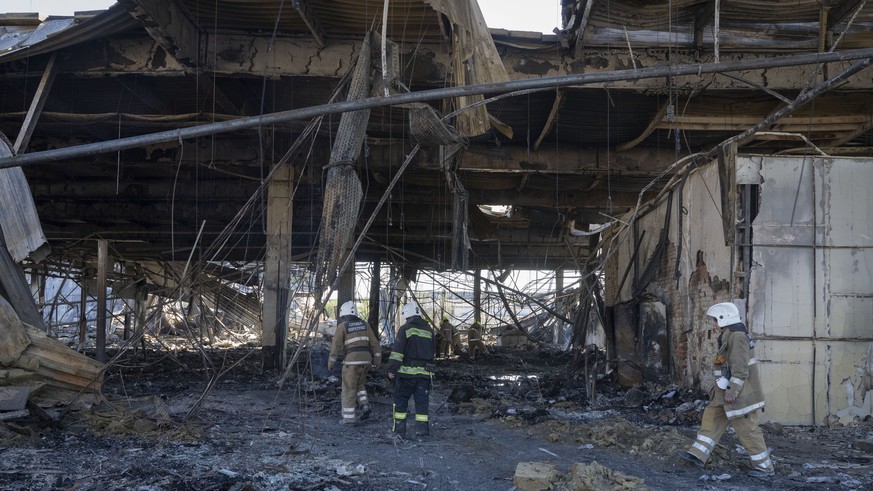 Ukrainian State Emergency Service firefighters work to take away debris at a shopping center burned after a rocket attack in Kremenchuk, Ukraine, Tuesday, June 28, 2022. (AP Photo/Efrem Lukatsky)