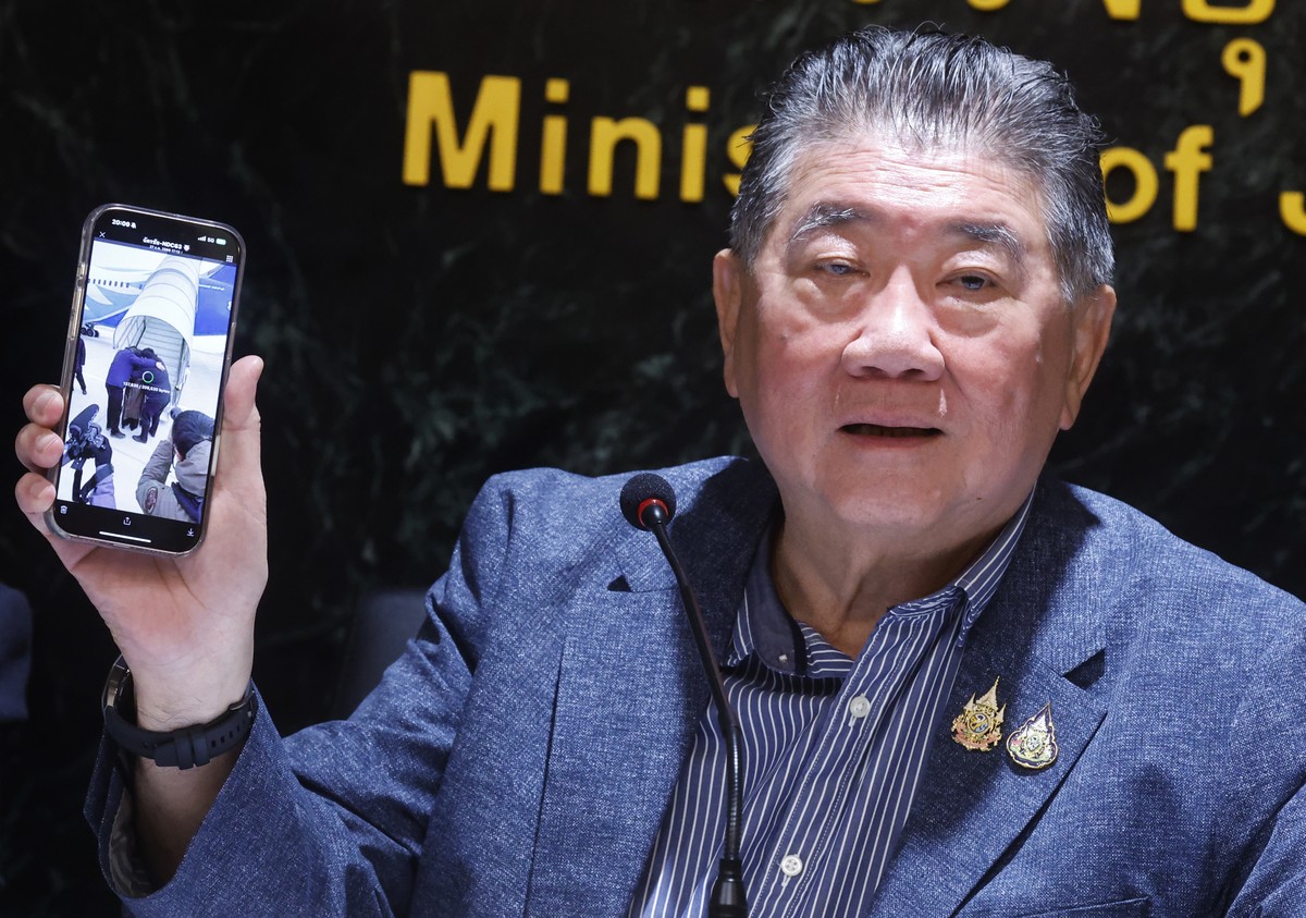 epa11928164 Thai Defense Minister Phumtham Wechayachai shows a picture on his mobile phone of Uyghur refugees upon their arrival at a airport in China, during a press conference on the deportation of  ...