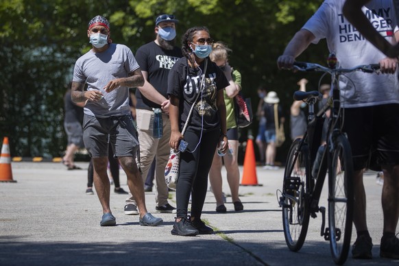 epa08540949 Masked people wait in a long and hot line at a walk-up coronavirus COVID-19 testing site at the Little 5 Points Center for Arts and Community in Atlanta, Georgia, USA, 11 July 2020. Due to ...