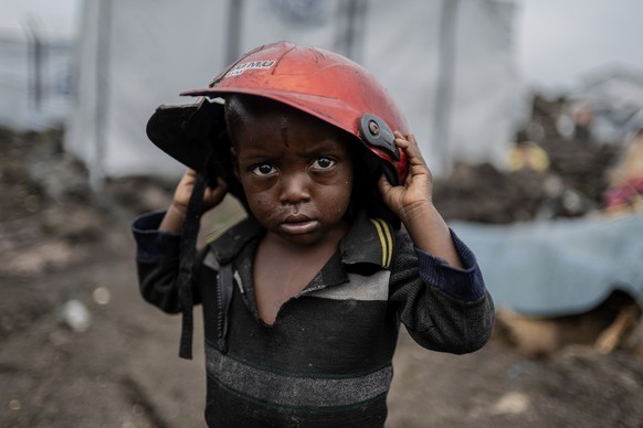 A child displaced by the fighting between M23 rebels and government soldiers holds a damaged helmet at the camp in Goma, Democratic Republic of the Congo, Tuesday, Feb. 11, 2025. (AP Photo/Moses Sawas ...