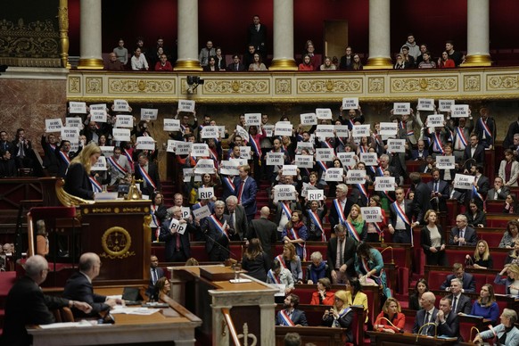 Far-left lawmakers respond, holding papers that read: 64 years.  It's no, at the National Assembly in Paris at the National Assembly in Paris, Monday, March 20, 2023. The French government is v ...