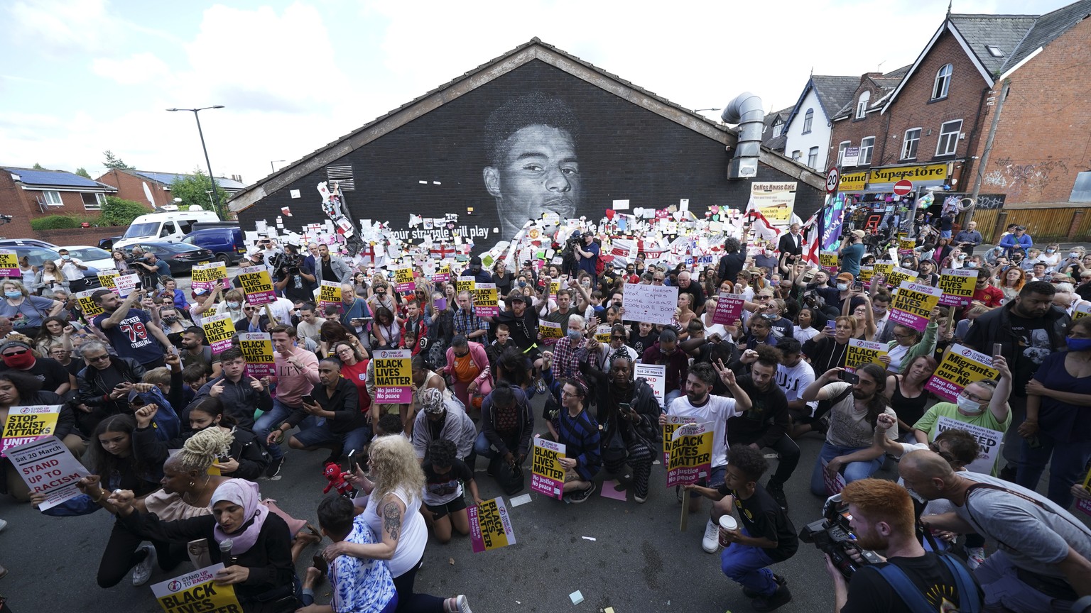 People take the knee during an anti-racism protest near a mural of Manchester United striker and England player Marcus Rashford, on the wall of the Coffee House Cafe on Copson Street, in Withington, M ...