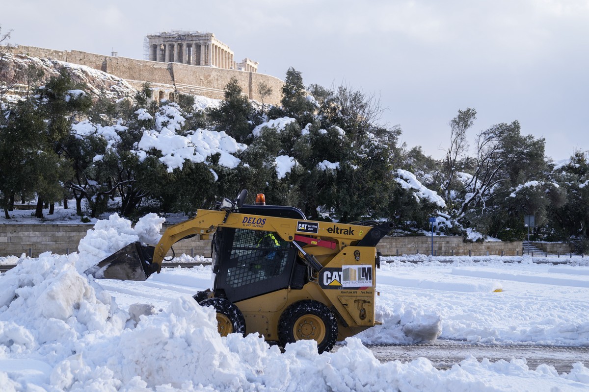 A snow plow clears a road in front of the ancient Acropolis hill, in Athens, on Tuesday, Jan. 25, 2022. A snowstorm of rare severity disrupted road and air traffic Monday in the Greek capital of Athen ...