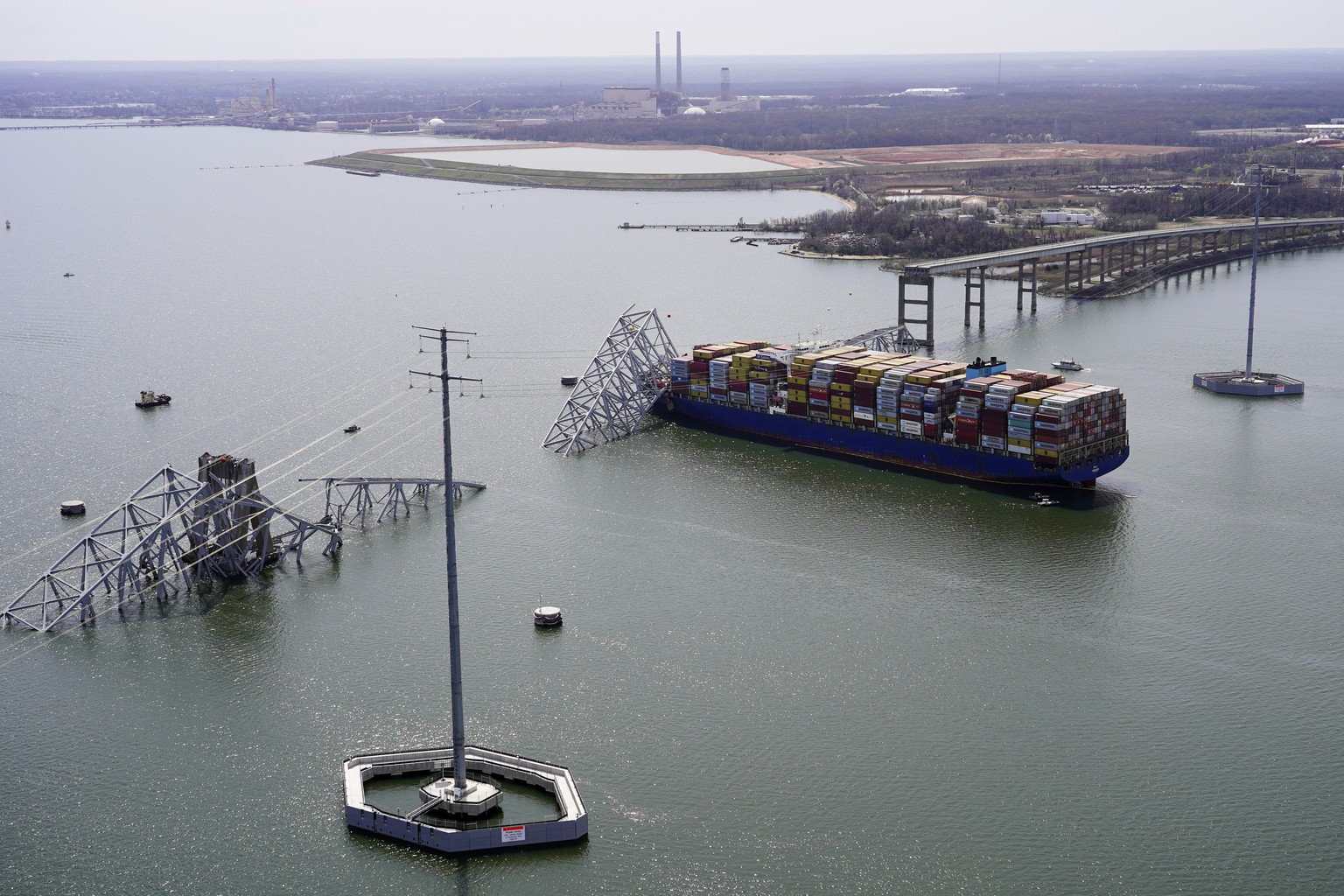 In this aerial photo released by the Maryland National Guard, the cargo ship Dali is trapped under part of the structure of the Francis Scott Key Bridge after the ship struck the bridge, Tuesday, March 26...