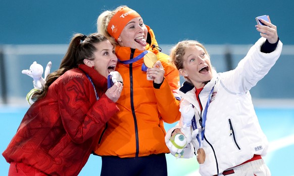 epa12765654 (L-R) Silver medalist Ivanie Blondin of Canada, Gold medalist Marijke Groenewoud of Netherlands, and Bronze medalist Mia Manganello of USA take a selfie on the podium during the medal cere ...