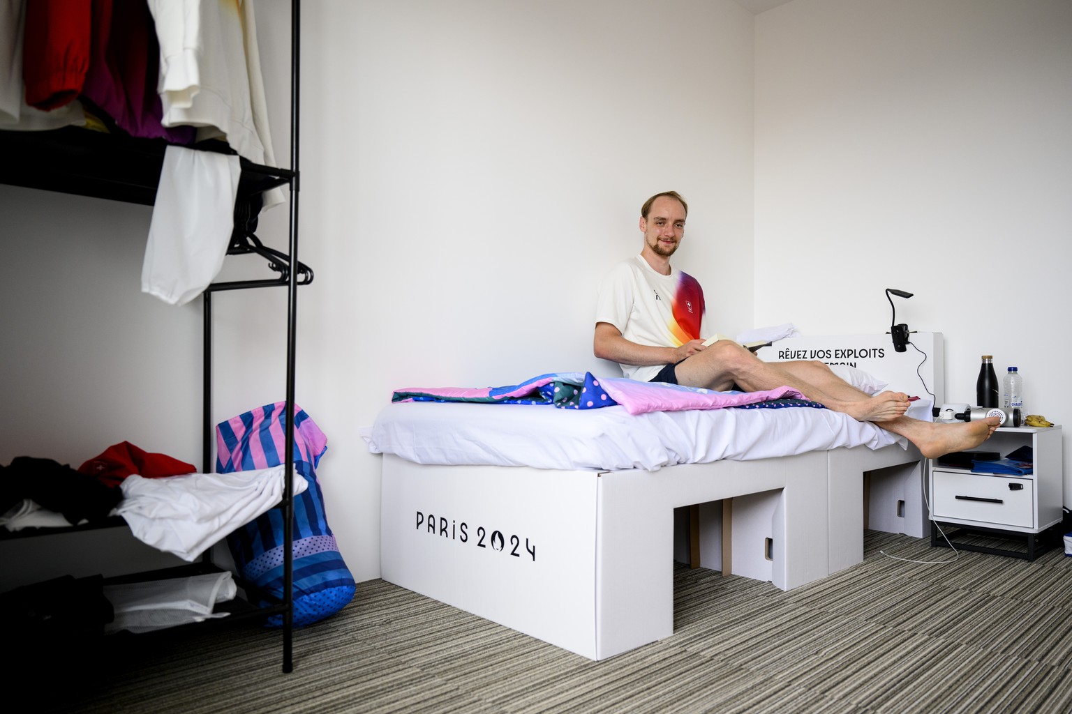 Swiss badminton athlete Tobias Kuenzi poses on a cardboard bed in his room of the building where Switzerland&#039;s athletes live during a media tour of the Olympic village of the 2024 Paris Summer Ol ...