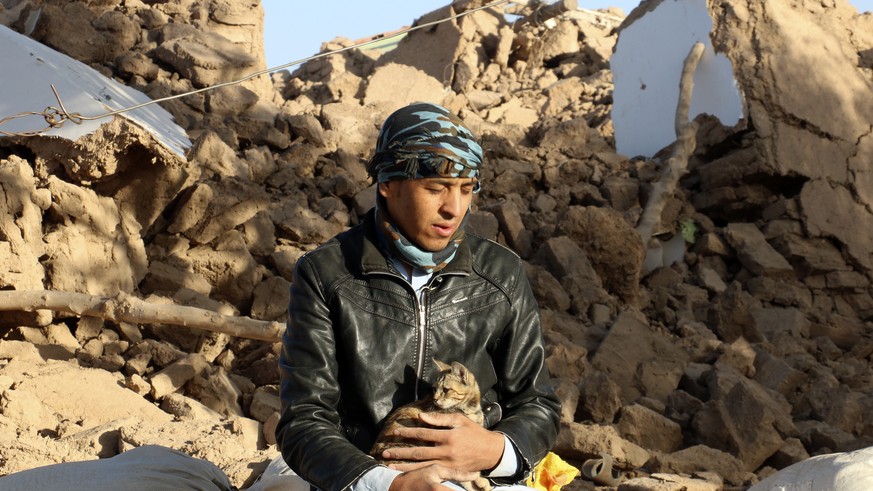 An Afghan boy hold his cat, as he sits in a courtyard of his destroyed home after an earthquake in Zenda Jan district in Herat province, of western Afghanistan, Sunday, Oct. 8, 2023. Powerful earthqua ...