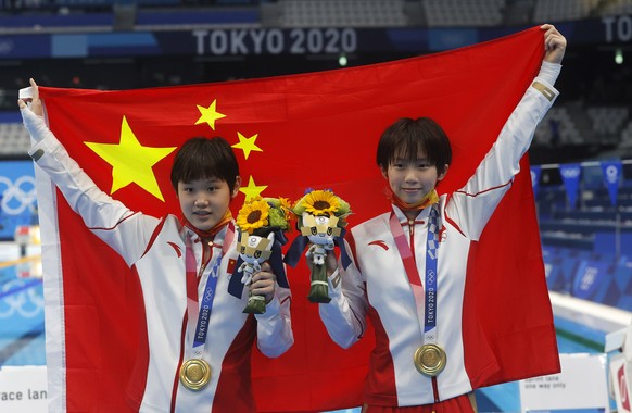 epa09369155 The gold medalist Yuxi Chen and Jiaqi Zhang of China celebrate after the Diving Women synchonised 10m platform final of the Tokyo 2020 Olympic Games at the Nippon Budokan arena in Tokyo, J ...