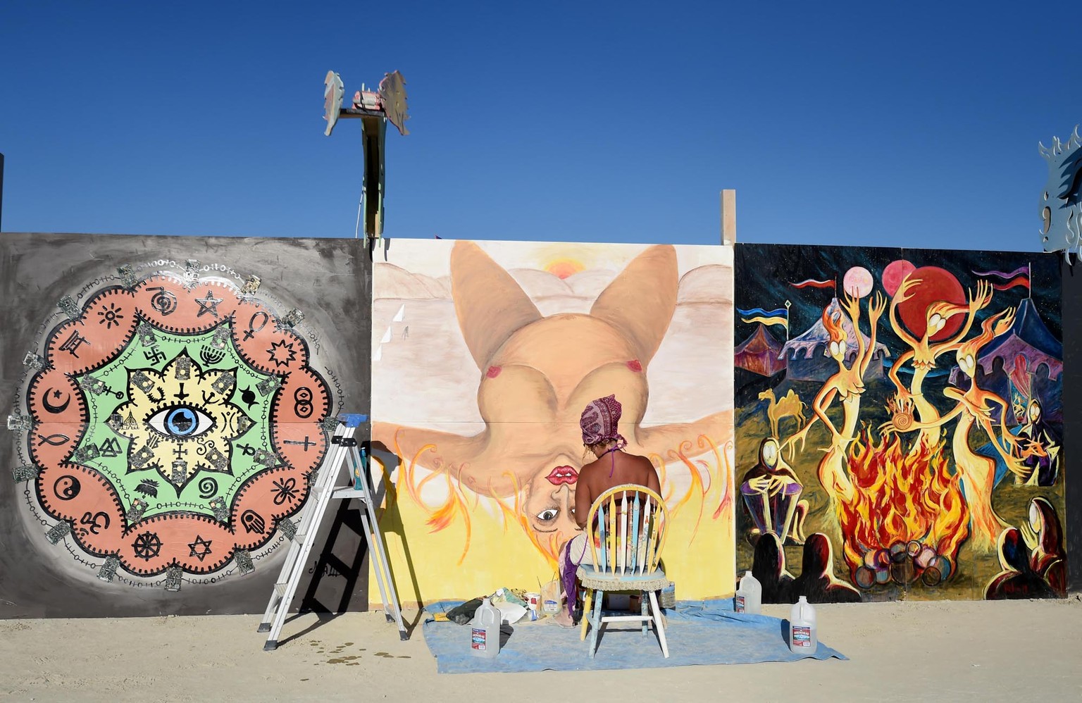 Artist Christina Minor paints on one of the panels around center camp at Burning Man in the Black Rock Desert in Gerlach, Nev. on Aug. 24, 2014, a day before the event opens to ticket holders. (AP Pho ...