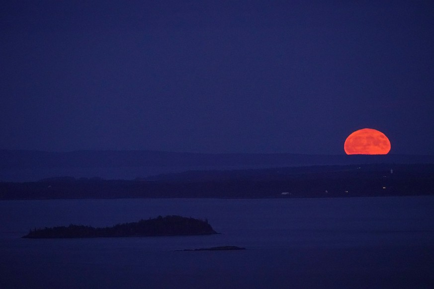 The supermoon rises behind Isle Au Haut in the distance, and North Haven Island, middle ground, Tuesday, Aug. 1, 2023, as viewed from Camden, Maine. (AP Photo/Robert F. Bukaty)