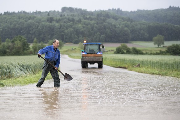 CAPTION CORRECTION - Ein Mann laeuft mit einer Schaufel auf einer ueberfluteten Strasse, aufgenommen am Mittwoch, 8. Juni 2016, in Dottikon. Durch den starken Regen und Unwetter kam es zu Ueberschwemm ...