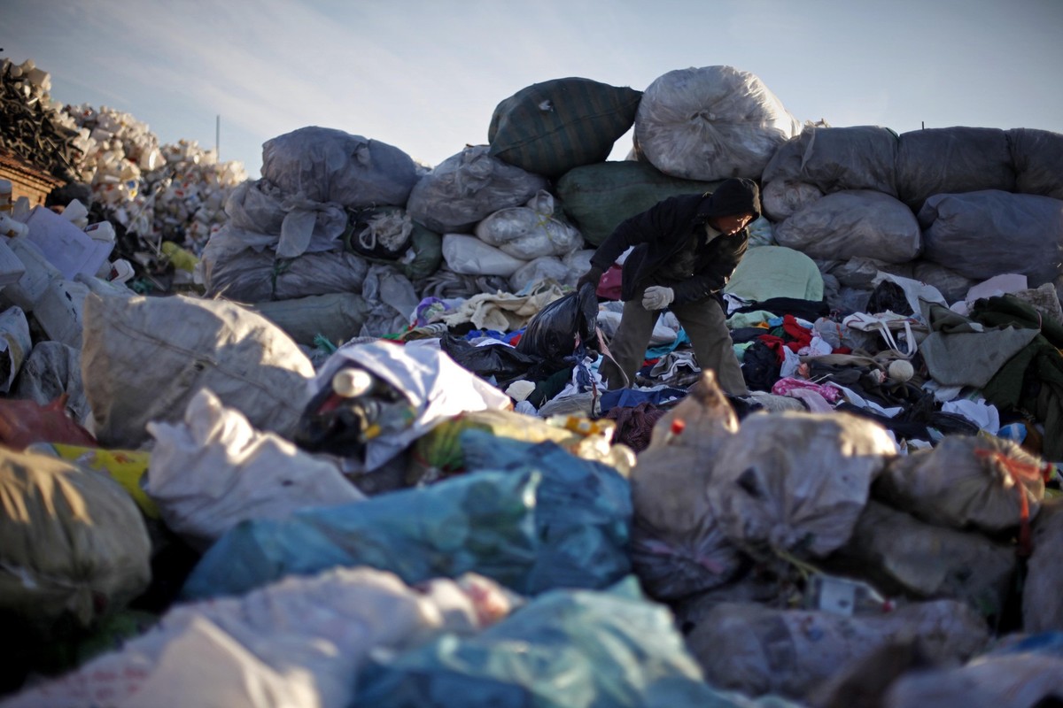 A Chinese man looks through discarded clothes at a recycling center in Beijing, China, Tuesday, Dec. 15, 2009. China, India and other developing nations boycotted U.N. climate talks Monday, bringing n ...