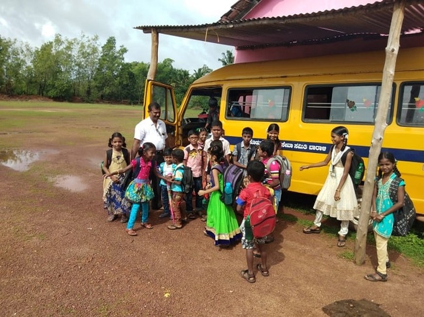 Dorflehrer Rajaram mit seinen Schülern vor dem neuen Schulbus von Baraali.