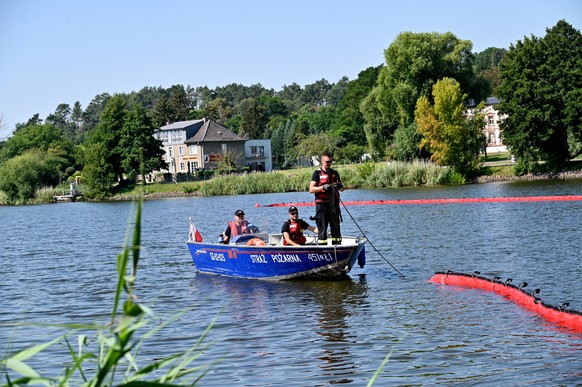 epa10124245 Firefighters from the State Fire Service install a flexible floating barrier on the Odra (Oder) River, aimed at catching more dead fish from its waters in Gryfino, in the West Pomeranian V ...