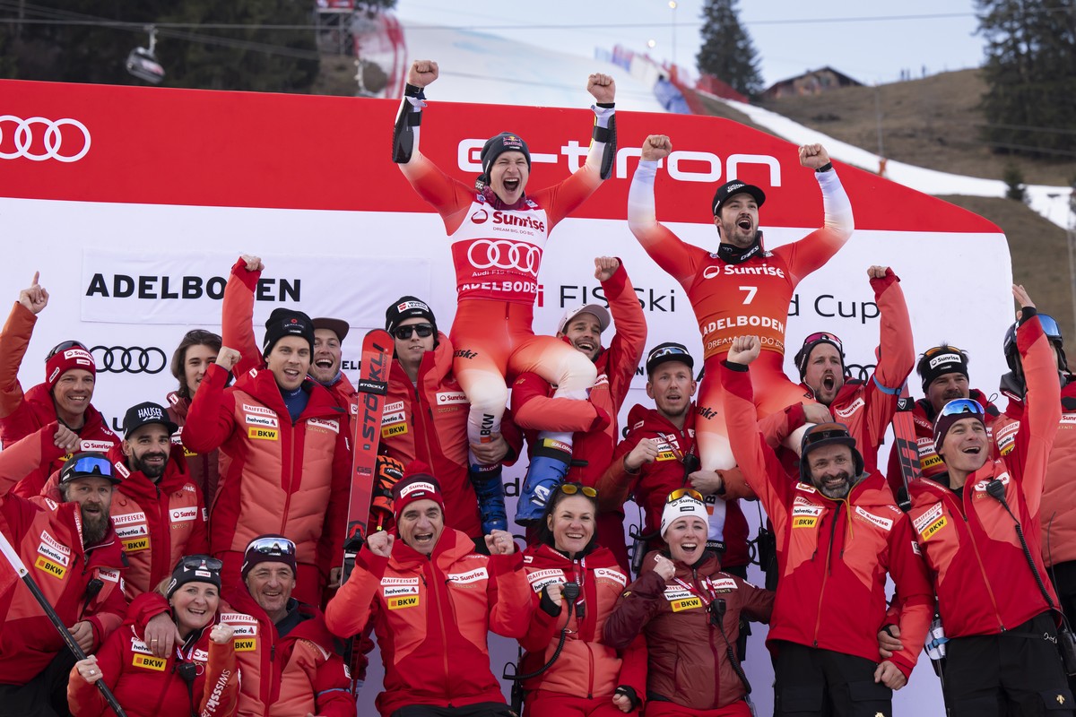 epa10394289 Winner Marco Odermatt (top C)of Switzerland and third placed Loic Meillard (top R) of Switzerland celebrate with the Swiss team members in the finish area after the Men's Giant Slalom ...