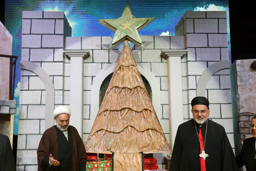 epa12593837 A Christian clergyman (R) and a Muslim clergyman (L) stand next to the Christmas tree crafted from two tonnes of soap after the curtain has been removed on the occasion of Christmas in Rou ...