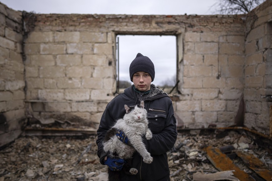 FILE - Danyk Rak, 12, holds a cat standing on the debris of his house destroyed by Russian forces' shelling in the village of Novoselivka, near Chernihiv, Ukraine, April 13, 2022. Danyk's fa ...
