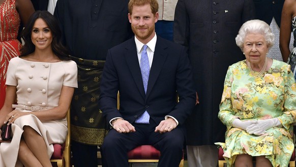 FILE - In this file photo from Tuesday, June 26, 2018, Britain's Queen Elizabeth, Prince Harry, and Meghan, Duchess of Sussex pose for a group photo at the Queen's Young Leaders Awards Ceremony in Buckingham...