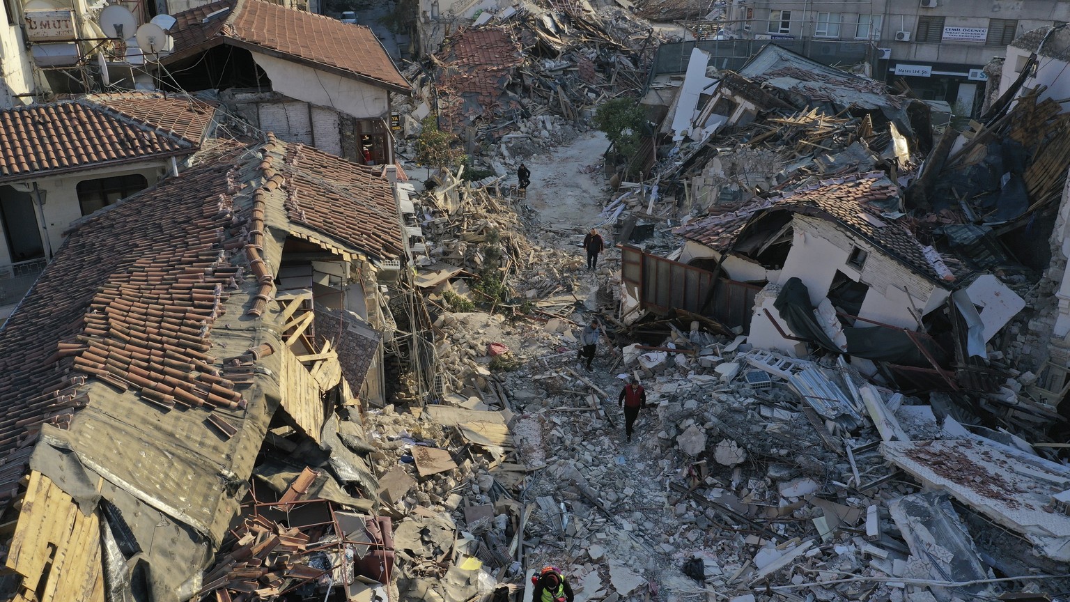 People walk among destroyed building in the old city of Antakya, southern Turkey, Monday, Feb. 13, 2023. Thousands left homeless by a massive earthquake that struck Turkey and Syria a week ago packed  ...