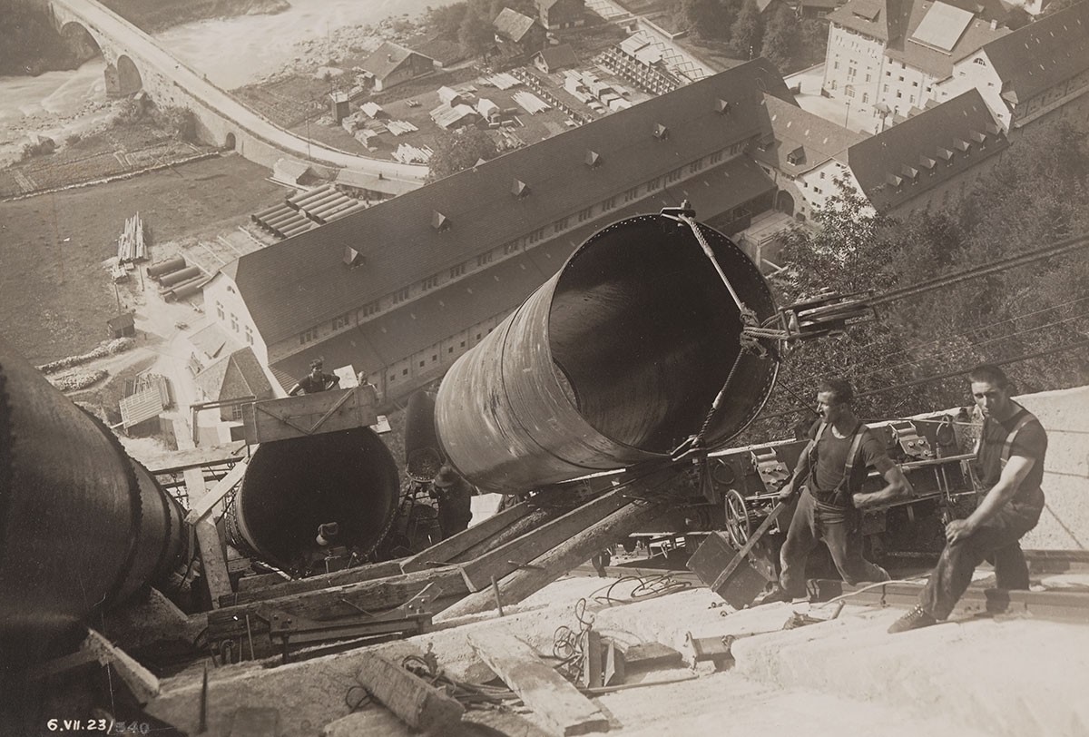 Abladen eines Rohres von der Standseilbahn für die Konstruktion der Druckleitung. Im Tal unten ist das Wasserkraftwerk Amsteg zu sehen. Aufnahme um 1920. 
https://www.sbbarchiv.ch/detail.aspx?id=49244 ...