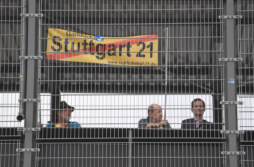 epa05542013 Stuttgart 21 opponents hold up a banner against the controversial Stuttgart 21 project behind the bounds of a pedestrian walk during the groundbreaking in front of the central railway stat ...