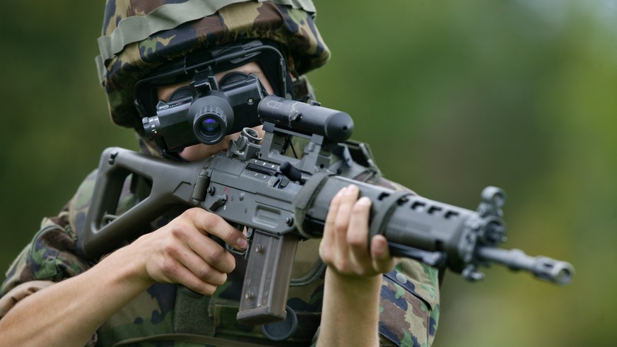 Ein Rekrut, mit einem Sturmgewehr Stgw 90 und Laserpointer bewaffnet, schaut anlaesslich der Rekrutenschule Panzer RS 21-2 am 29. September 2004 auf dem Gelaende des Waffenplatz Thun durch einen Restl ...