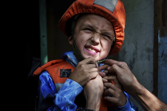 A Fenix team rescue worker places a helmet on Bohdan Scherbyna, 9, as he is evacuated with his mother Maryna Scherbyna and 14-year-old sister Angelina Scherbyna, as locals are moved from Selidove to s ...
