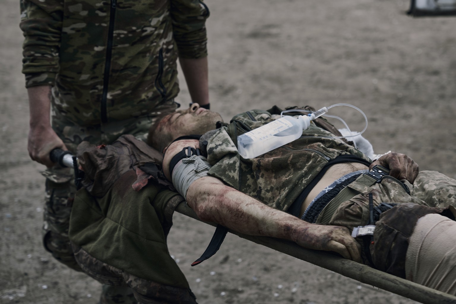 A Ukrainian soldier carries his wounded fellow at a medical stabilisation point near Bakhmut, Donetsk region, Ukraine, Thursday, April 27, 2023. (AP Photo/Libkos)