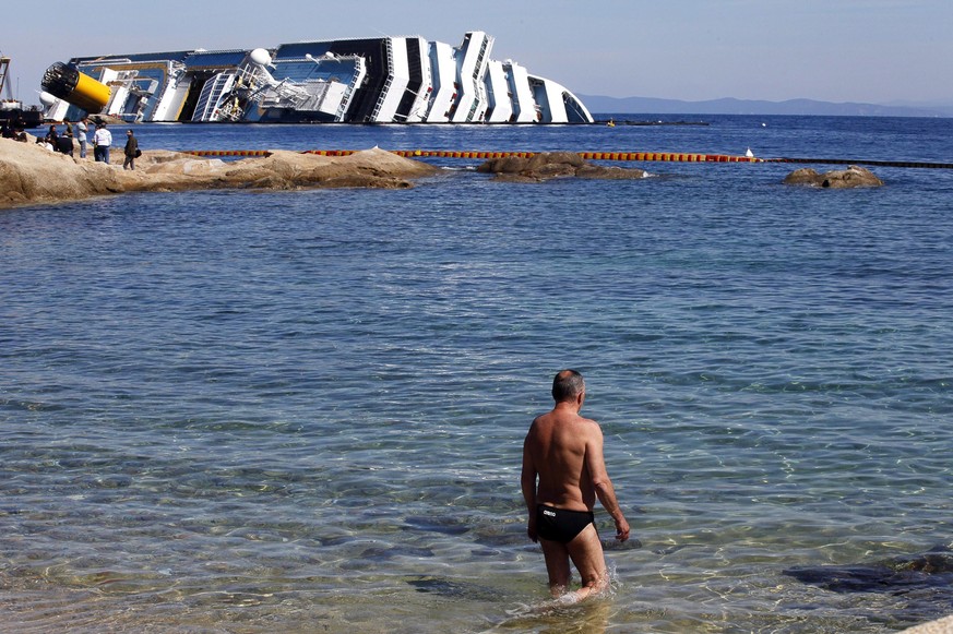 epa09680227 (FILE) - A tourist goes swimming with the wreck of the stricken cruise liner Costa Concordia on the background near the harbour of Giglio Island, Italy, 09 April 2012 (reissued 12 January  ...