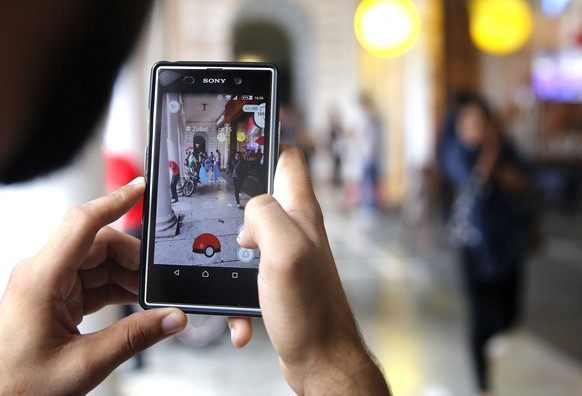 epa05447426 An Indian Pokemon Go game enthusiast tries to catch a Pokemon character after locating it, at Connaught Place in New Delhi, India, 29 July 2016. According to media reports, the launch of P ...