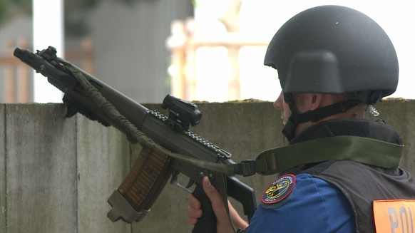 Mehrere Polizistinnen und Polizisten bezogen mit Schutzhelm und Maschinenpistole Stellung rund um die betroffene Liegenschaft.