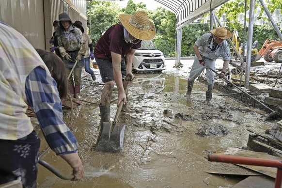 People clear the mud after torrential rain in Kurume, Fukuoka prefecture, southern Japan Tuesday, July 11, 2023. Rain falling in the regions of Kyushu and Chugoku since the weekend caused flooding alo ...