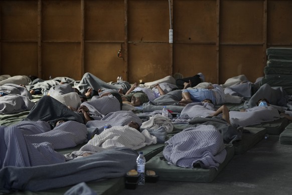 Survivors of a shipwreck sleep at a warehouse at the port in Kalamata town, about 240 kilometers (150 miles) southwest of Athens, Wednesday, June 14, 2023. A fishing boat carrying migrants capsized an ...