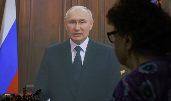 epaselect epa10709014 A woman watches Russian President Vladimir Putin delivering a televised address to the nation in Moscow, Russia, 24 June 2023. Putin said counter-terrorism measures were enforced ...