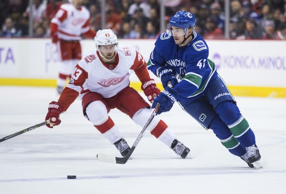 Vancouver Canucks&#039; Sven Baertschi, right, of Switzerland, passes the puck while being watched by Detroit Red Wings&#039; Darren Helm during the first period of an NHL hockey game, Monday, Nov. 6, ...