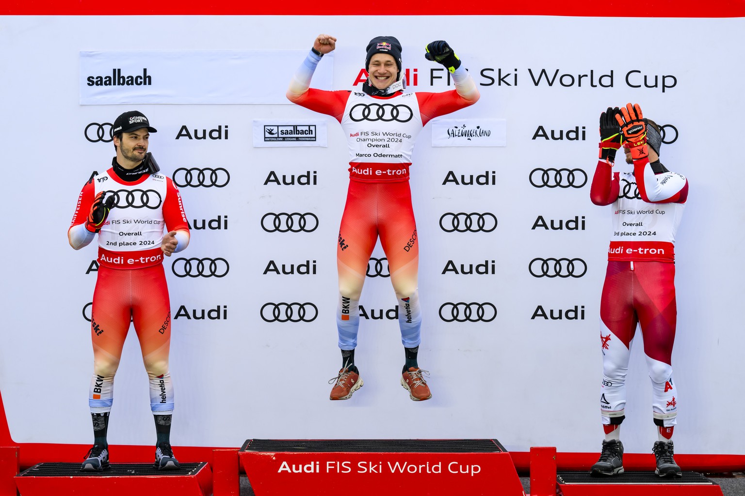 Marco Odermatt of Switzerland, center, winner of the men&#039;s world cup overall ranking, celebrates with second placed Loic Meillard of Switzerland, left, and third placed Manuel Feller of Austria,  ...
