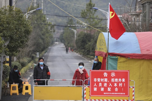 Volunteers stand beneath a Communist Party flag as they man a barricade checkpoint at a village in Hangzhou in eastern China&#039;s Zhejiang Province, Monday, Feb. 3, 2020. China sent medical workers  ...