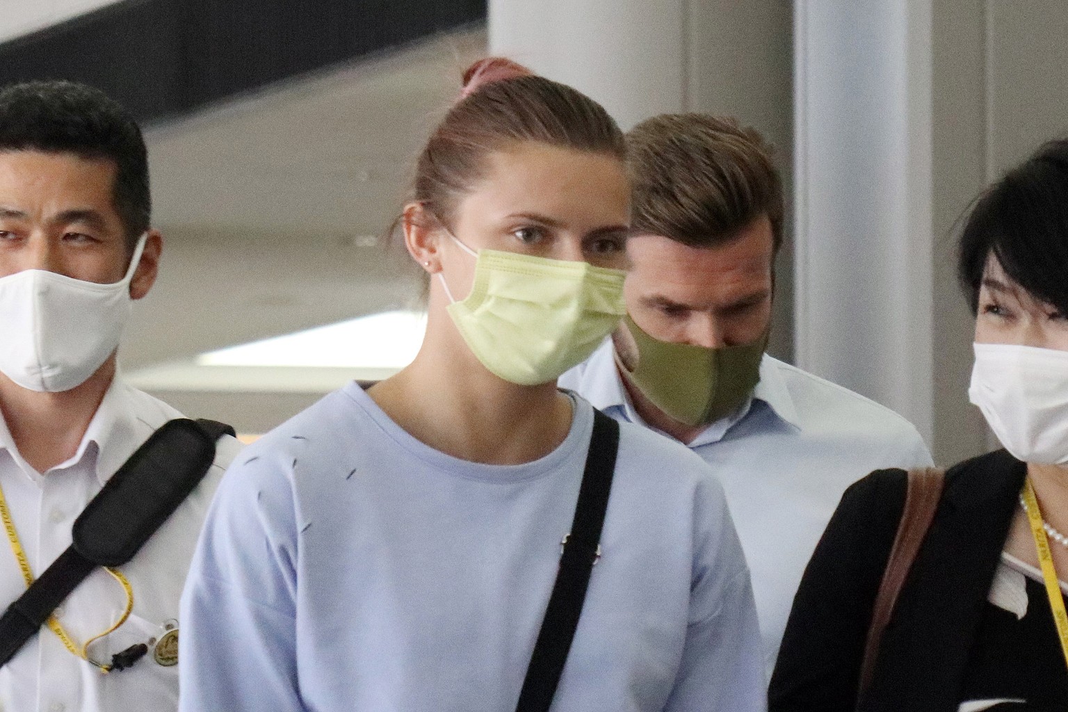 epa09393416 Belarusian athlete Krystsina Tsimanouskaya (C) walks on her way to board an aircraft at Narita airport near Tokyo, Japan, 04 August 2021. Krystsina Tsimanouskaya was forcibly pulled out fr ...