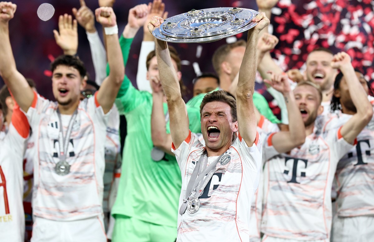 epa12089669 Thomas Mueller of Bayern Munich lifts the Bundesliga Meisterschale Trophy as his teammates celebrate their German Bundesliga championship title after the German Bundesliga soccer match bet ...