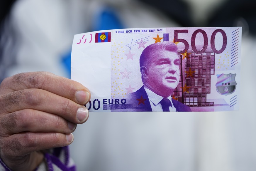 A fan holds fake money that shows Joan Laporta, president of FC Barcelona before the Spanish Copa del Rey semi final, first leg soccer match between Real Madrid and Barcelona at Santiago Bernabeu stad ...