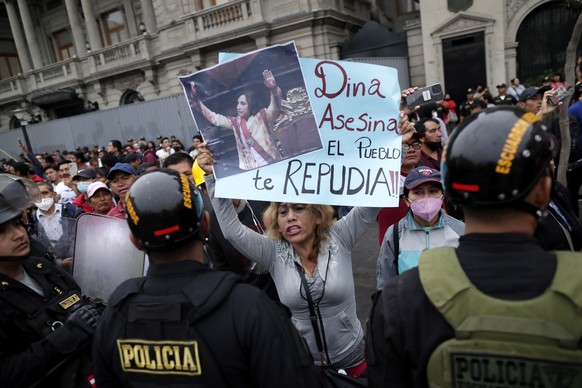 epa10369169 A protester opposed to the government holds a sign reading &#039;Murderer Dina, the people reject you&#039; during the pro-government &#039;March for Peace&#039;, in Lima, Peru, 16 Decembe ...