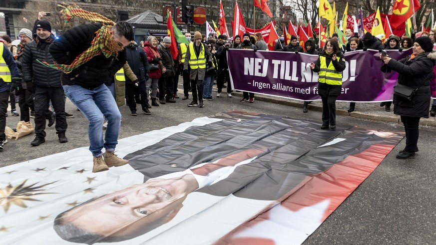 A protestor prepares to jump on a banner with the image of Turkish President Recep Tayyip Erdogan during a demonstration organised by The Kurdish Democratic Society Center in Sweden, as Sweden seeks T ...
