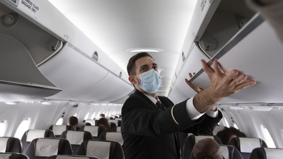 epa08486922 A cabin crew member of Swiss International Air Lines, wearing a face mask, prepares the aircraft prior to departure to London at the Geneva Airport, in Geneva, Switzerland, 15 June 2020. F ...