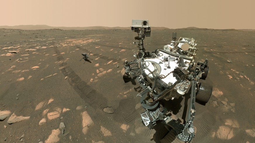 This Tuesday, April 6, 2021 image made available by NASA shows the Perseverance Mars rover, foreground, and the Ingenuity helicopter about 13 feet (3.9 meters) behind. This composite image was made by ...