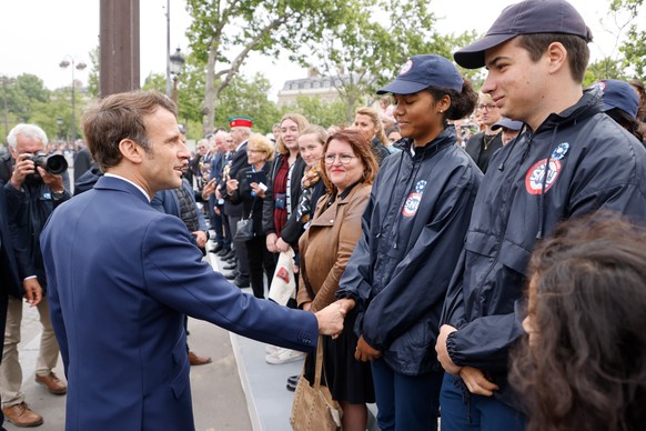 epa09933235 French President Emmanuel Macron (L) greets members of the Universal National Service (Service national Universel, SNU) (R) at the Arc de Triomphe as they attend the ceremonies marking the…
